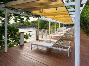 a row of lounge chairs on a wooden deck at Hotel Roatán Media Luna Resort, Affiliated by Meliá in First Bight