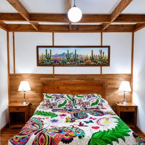 a bedroom with a bed with a colorful comforter and two lamps at Apart Hotel Caldera - Room in Caldera