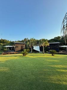 a green yard with palm trees and a building at Le Lodge Mimitsu in Hyuga
