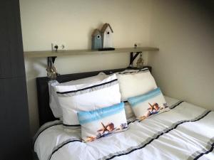 a bed with white pillows and a shelf on the wall at Place2BEach-Bungalow in Noordwijk aan Zee