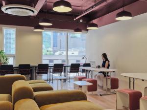 a woman sitting at a table in a room with a laptop at Seoul ABC Hostel in Seoul