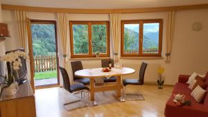ein Wohnzimmer mit einem Tisch, Stühlen und Fenstern in der Unterkunft Apart Franziska in Kauns