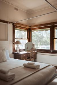a bedroom with a bed with a desk and windows at Warburton Stays Grand View in Warburton +44 photos