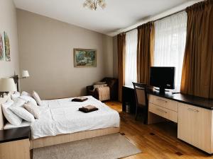 a bedroom with a bed and a desk with a television at Mini-Hotel Under The Roof in Lviv
