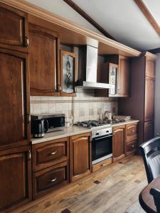 a kitchen with wooden cabinets and a stove top oven at Mini-Hotel Under The Roof in Lviv
