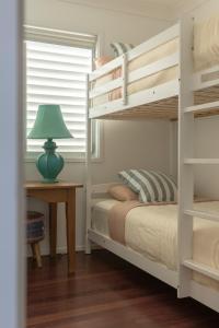a bedroom with a bunk bed and a table with a lamp at Bay Properties Pacific Lodge in Yamba