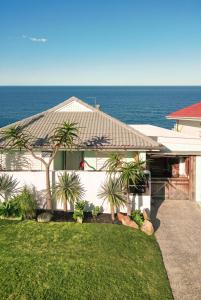 a white house with palm trees in front of the ocean at Bay Properties Pacific Lodge in Yamba