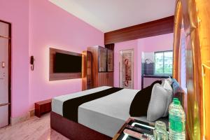a pink bedroom with a bed and a tv at Hotel O Bhubaneswar New Station Road in Bhubaneshwar