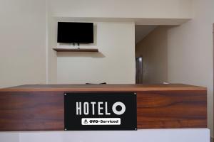 a hotel sign on a counter with a tv on a wall at Super Hotel O Phase 2 Christ Nagar Bangalore in Bangalore