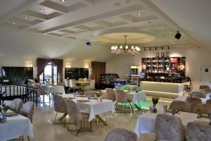 a restaurant with white tables and chairs and a chandelier at Northern City Hotel in Zaqatala