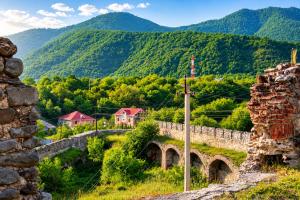 an old stone bridge with mountains in the background at Northern City Hotel in Zaqatala +22 photos