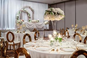 a banquet room with white tables and chairs and flowers at Holiday Inn Los Angeles Gateway-Torrance by IHG in Torrance +51 photos