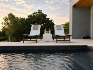 two chairs and a table next to a swimming pool at L'Escapade Caramanaise in Caraman