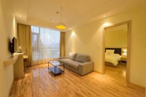 a living room with a couch and a bed and a mirror at Hanting Hotel Shanghai Wujiaochang in Shanghai