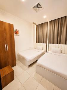 a hotel room with two beds and a cabinet at Atlantis International Hotel Apartments in Kuwait