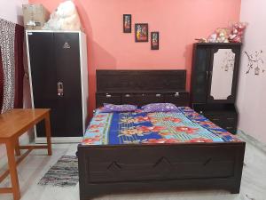a bedroom with a bed and a table and a refrigerator at SHYAMSHOBHA NIWAs in Chandauli