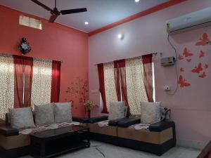 a living room with two couches and red walls at SHYAMSHOBHA NIWAs in Chandauli