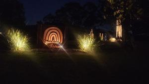 a sign with lights in the grass at night at Three-Kalm & Four-Sol by Tiny Away in Rainbow Flat