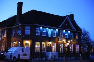 uma carrinha branca estacionada em frente a um edifício com janelas iluminadas em The Bull and Bush Hotel Kingston em Kingston upon Thames