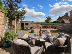 a patio with chairs and a table in a yard at 1 Church Barns in Great Driffield