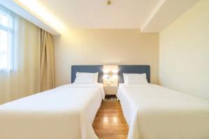 two beds in a room with white sheets at Hanting Hotel Shanghai Wujiaochang in Shanghai