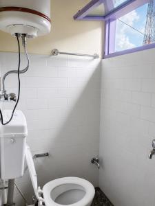 a bathroom with a toilet and a window at Jain Residency in Manāli