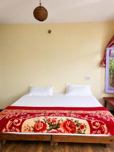 a bed with a red blanket on top of it at Jain Residency in Manāli +15 photos