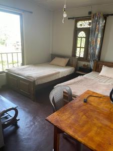 a room with two beds and a table and a window at Thumb Up Family Rest in Haputale