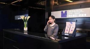 a woman talking on a cell phone behind a counter at J Link Hotel in Hong Kong