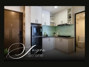 a kitchen with white cabinets and a black refrigerator at Saigon Serene - SOHO Residence - Stay in District 1 in Ho Chi Minh City