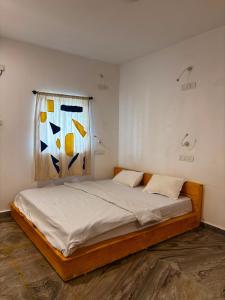 a bedroom with a bed with a painting on the wall at Horn Ok Please Hostel Mandrem in Mandrem