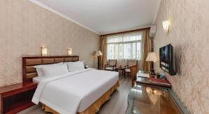 a bedroom with a large white bed and a television at Zhenxing Hotel in Shenzhen