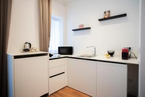 a white kitchen with white cabinets and a sink at Palazzo del Poeta - Dimora Contemporanea in Palermo