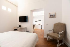 a bedroom with a bed and a chair and a television at Palazzo del Poeta - Dimora Contemporanea in Palermo