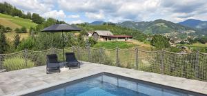 a swimming pool with two chairs and an umbrella at Landhaus Pool and Relax in Bruck an der Mur
