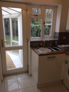 een keuken met een wastafel en 2 ramen bij Cosy 3 bed detached house Birmingham in Birmingham