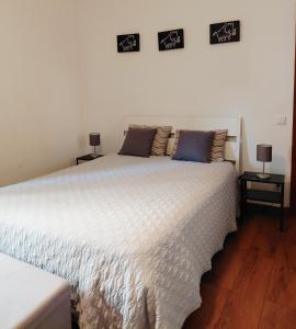 a bedroom with a large white bed with two lamps at De Cá - suite com acesso independente e kitchenette in Lousã