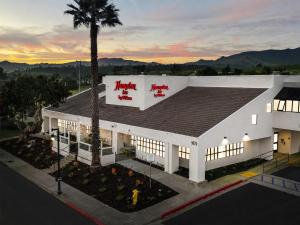 a white building with a palm tree in front of it at Hampton Inn San Simeon Cambria in San Simeon