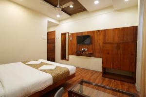 a hotel room with two beds and a glass table at Hotel Madhuri Executive in Kolhapur
