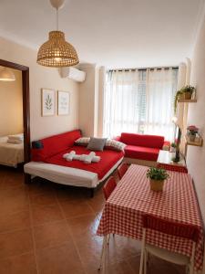 a living room with a red couch and a table at APARTAMENTOS VIALIA SOL y PLAYA in Málaga +13 photos