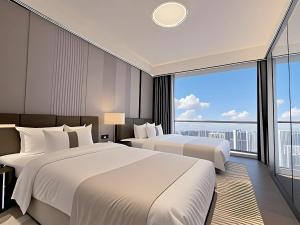 two beds in a hotel room with a large window at Ruilan Courtyard in Shenzhen