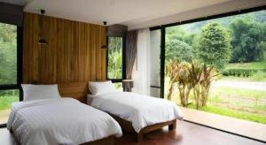 two beds in a bedroom with a large window at Villa De View in Ban Tham