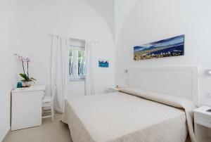 a white bedroom with a white bed and a window at Villa Pollio Guest House in Anacapri