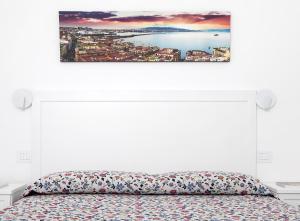 una camera bianca con un letto e un dipinto sul muro di Villa Pollio Guest House ad Anacapri