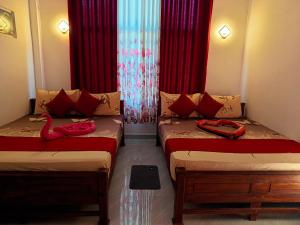 two twin beds in a room with red curtains at The Heaven Sorabora in Mahiyangana +112 photos