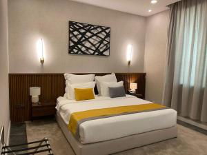 a bedroom with a large bed with yellow and white pillows at شير فل الرس in Ar Rass