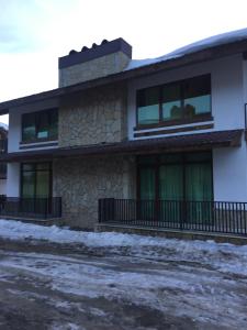 une maison avec des fenêtres vertes et de la neige devant elle dans l'établissement Villa (second floor) in CRYSTAL, à Bakuriani