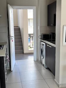 a kitchen with a washing machine and a staircase at Modern Heritage Condo in Fourways +6 photos