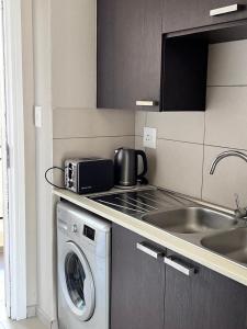 a kitchen with a washing machine and a sink at Modern Heritage Condo in Fourways