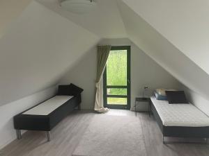 a attic room with two beds and a window at Spacious fullyequipped houses in Vordingborg